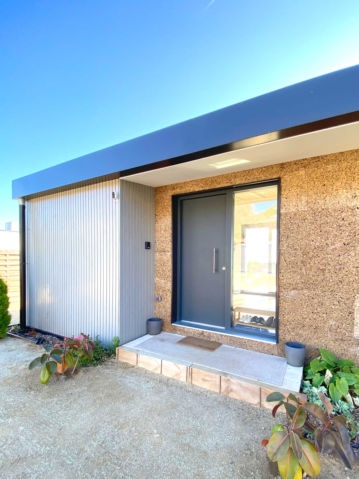 Puerta de entrada de aluminio negro integrada en fachada de vivienda contemporánea en Argentona