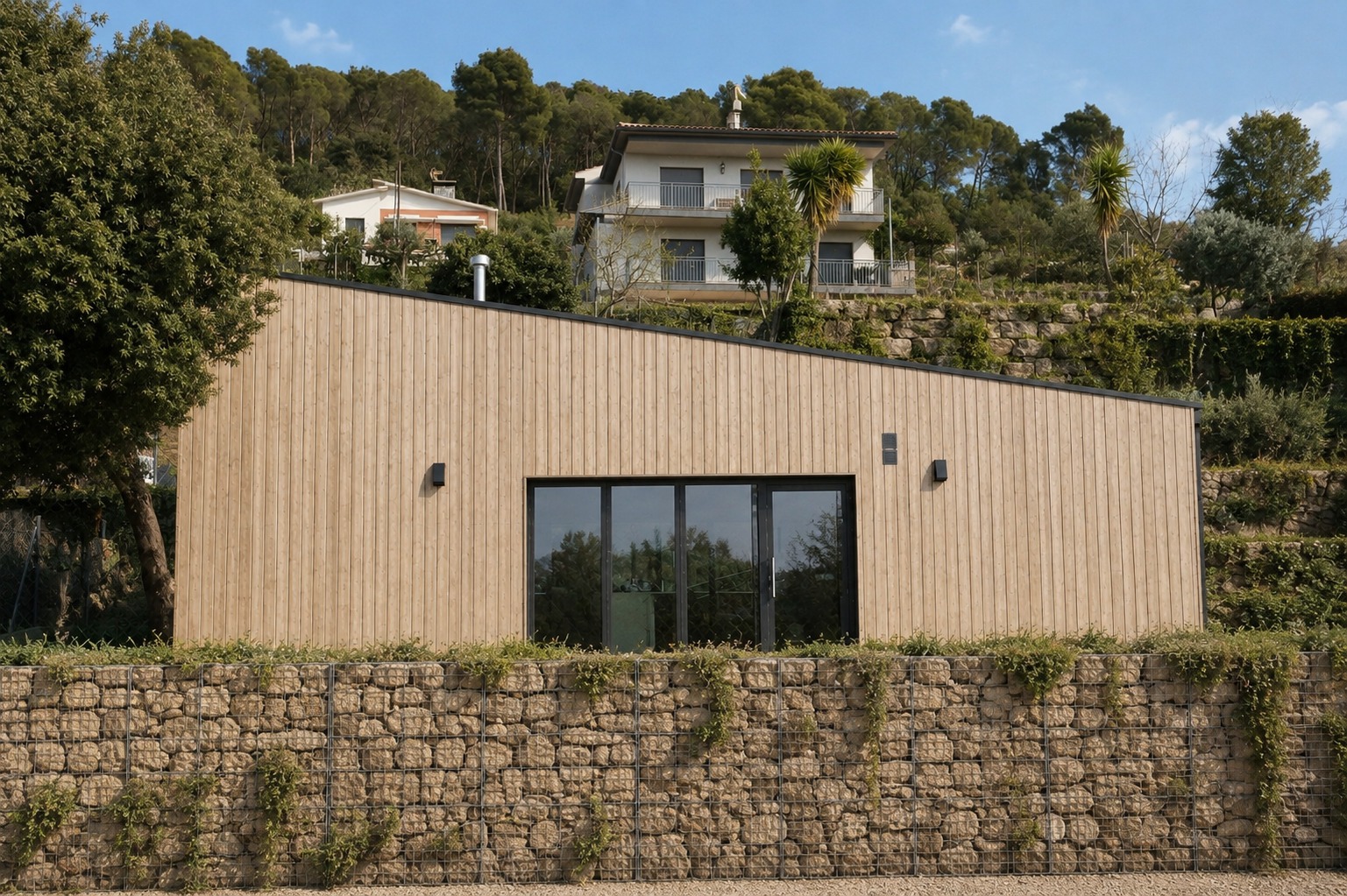 Vivienda en Bigues i Riells con gran corredera de aluminio negro integrada en fachada de madera