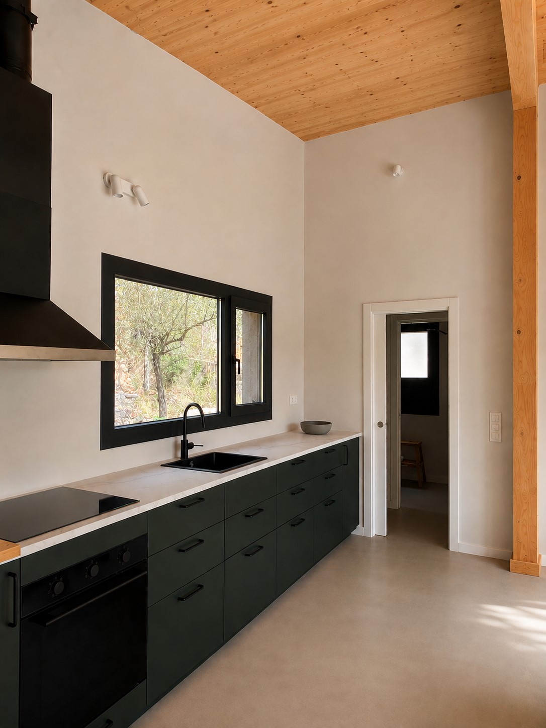 Cocina de vivienda en Canyelles con ventana de aluminio oscura integrada en el hueco