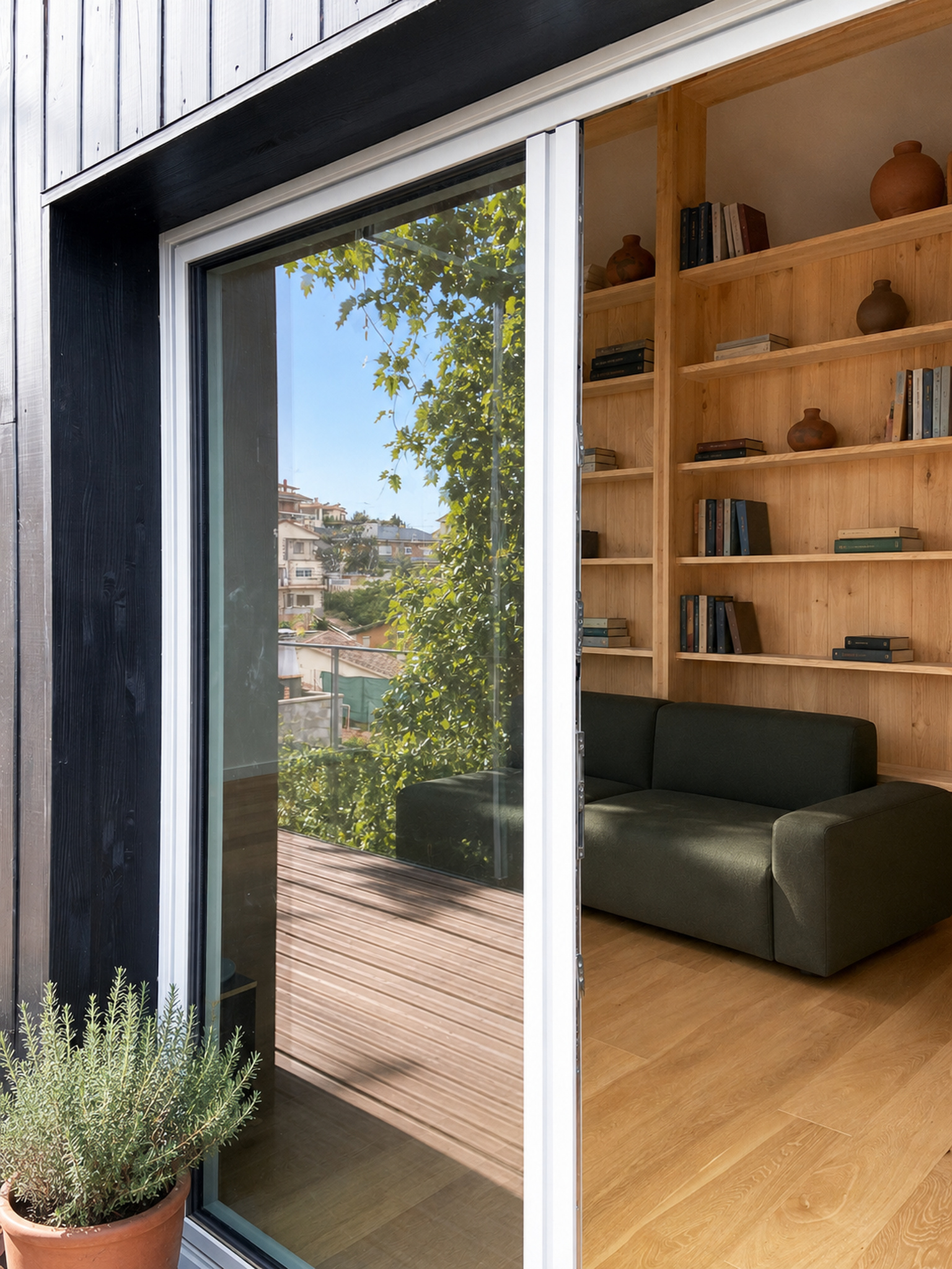 Gran hueco acristalado con carpintería de aluminio integrado en fachada de madera negra en Lliçà d’Amunt