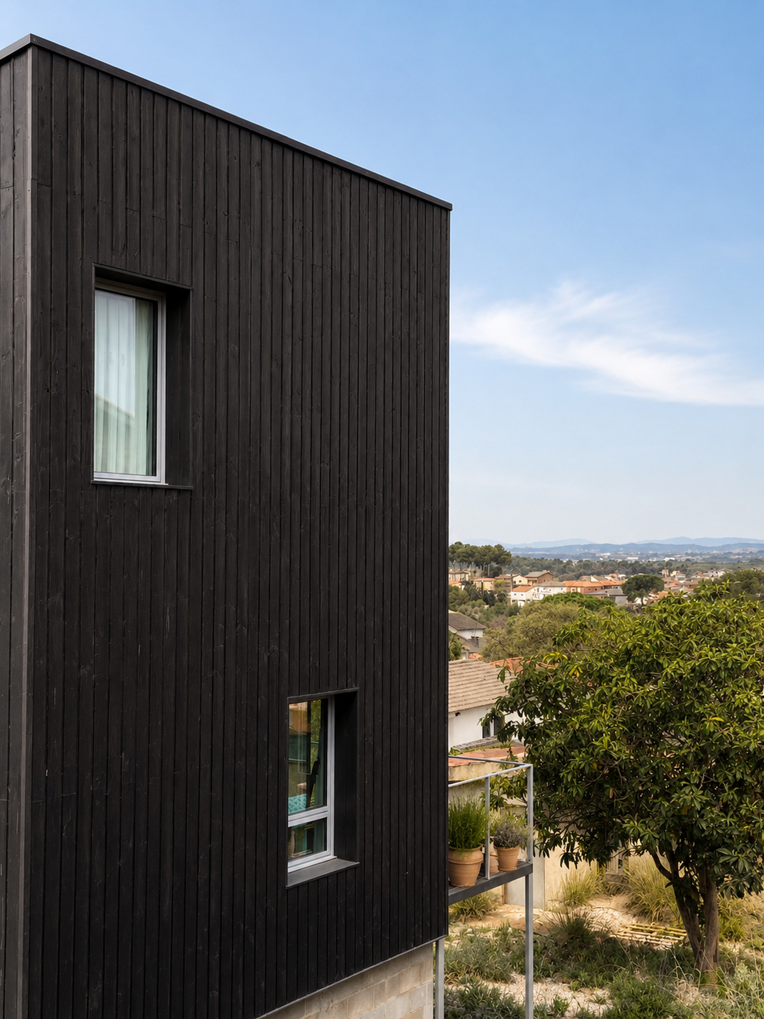 Huecos de aluminio integrados en una fachada de madera negra en Lliçà d’Amunt