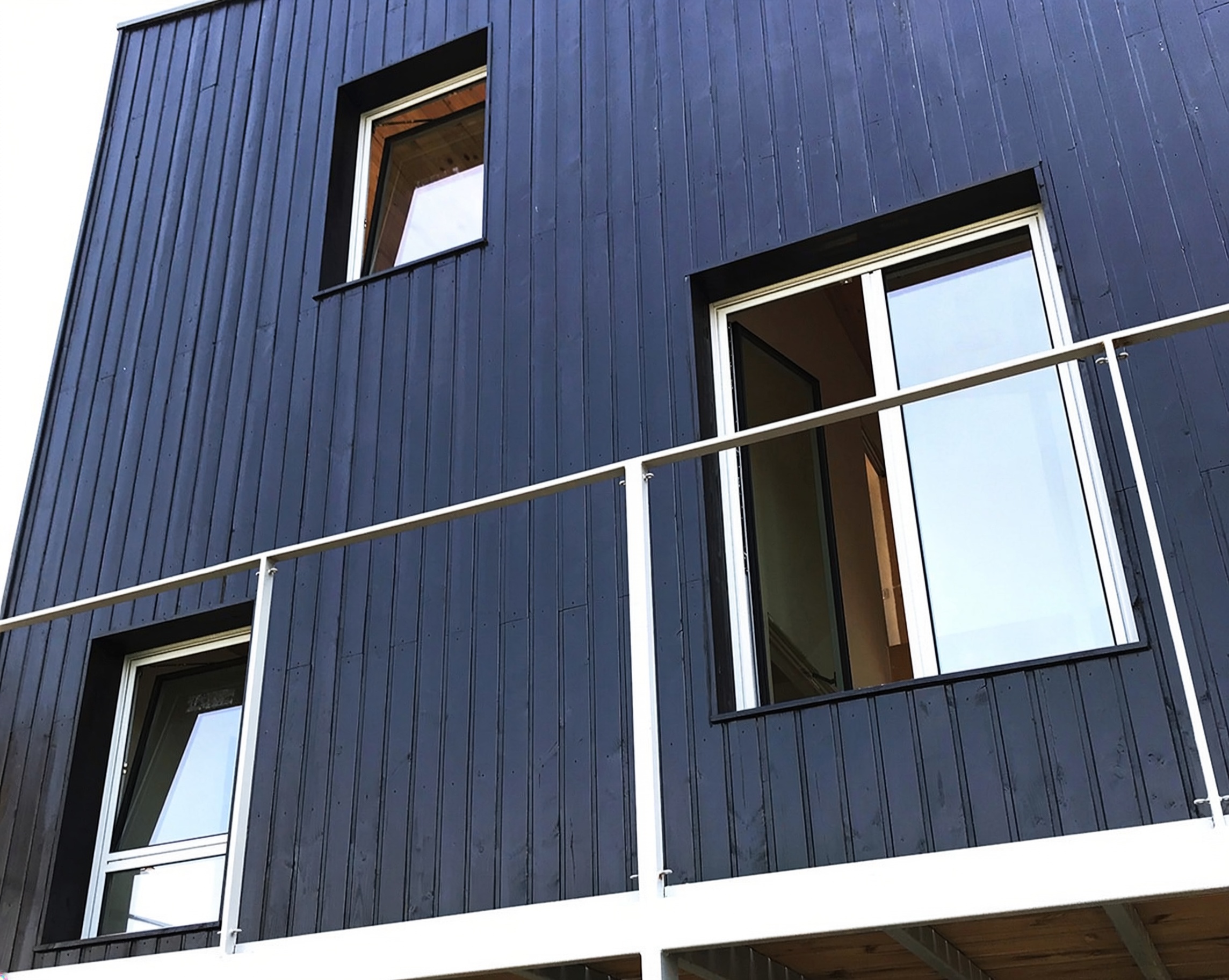 Ventanas verticales de aluminio integradas en fachada de madera negra en Lliçà d’Amunt